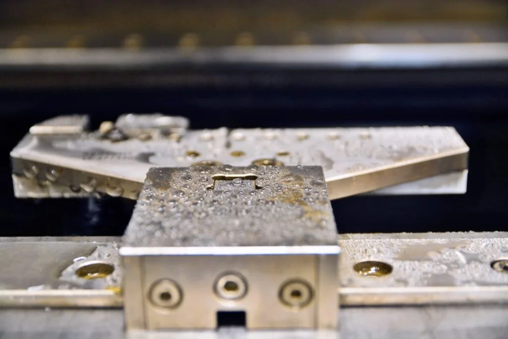 Elektroerosionsbearbeitung (EDM) mit Wasser, das an der bearbeiteten Metalloberfläche sichtbar ist.